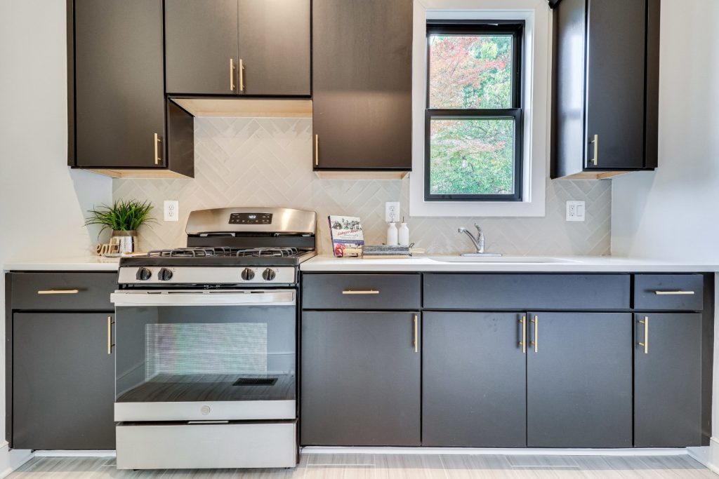 Spice kitchen with brown cabinets, a window, and gold hardware. 