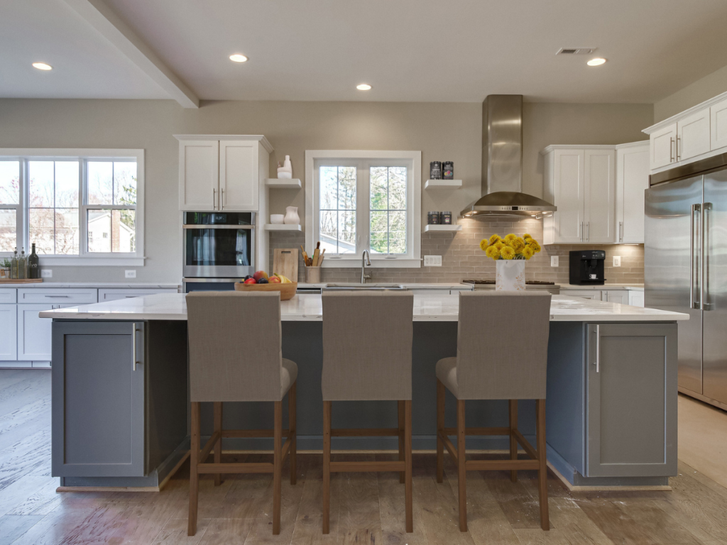 Kitchen with white cabinets and a gray island. Tan glossy backsplash. Mix of floating shelves and traditional cabinetry. 